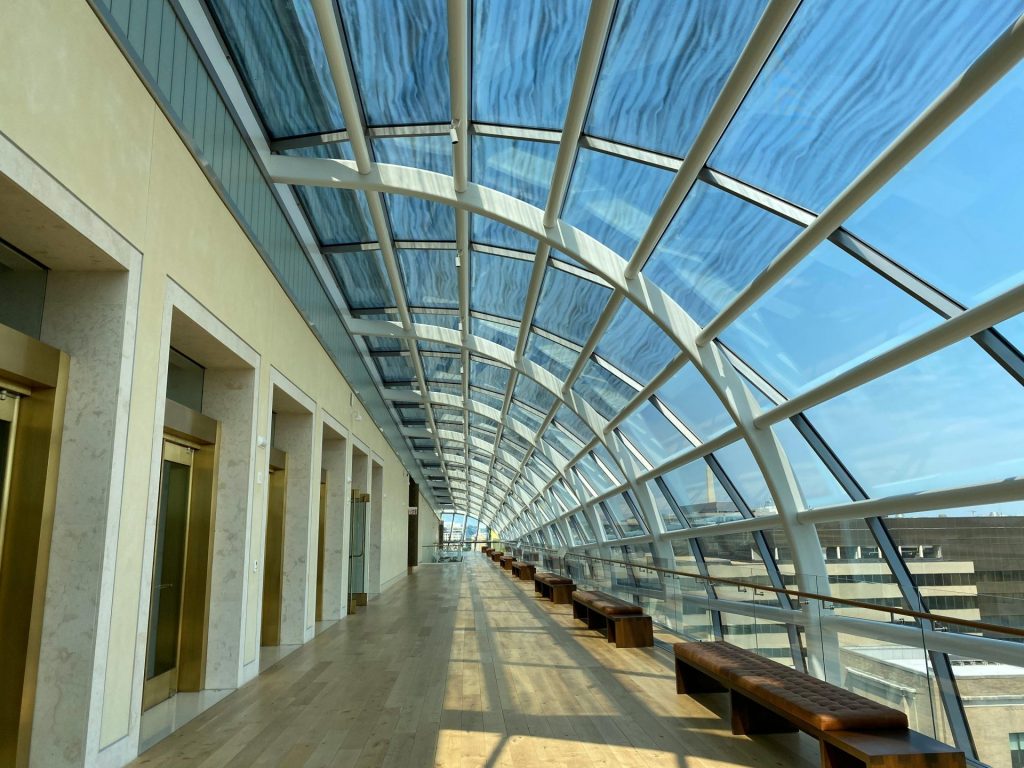 Ein geräumiger, moderner Flur mit Glasfenstern, Bänken und freiem Blick nach draußen.